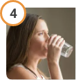 Woman drinking water after taking CREON® (pancrelipase) Delayed Release Capsules.