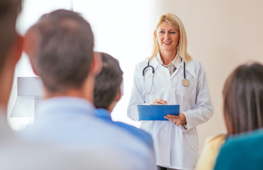 Female doctor addressing a room of individuals.